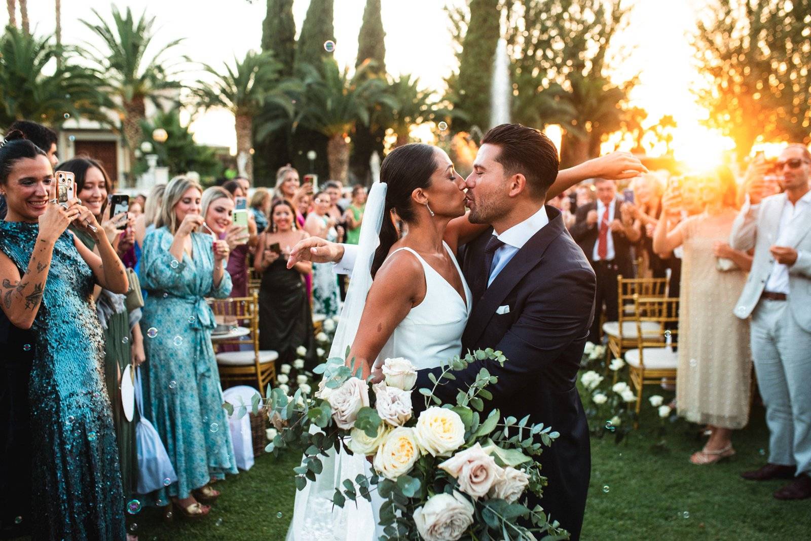 Boda en Granada en la que los novios se besan mientras todos los invitados los rodean haciéndoles fotos con los móviles