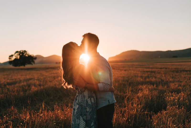 Sesión de fotos en pareja en Granada: pareja besándose a contraluz en una puesta de sol en el campo