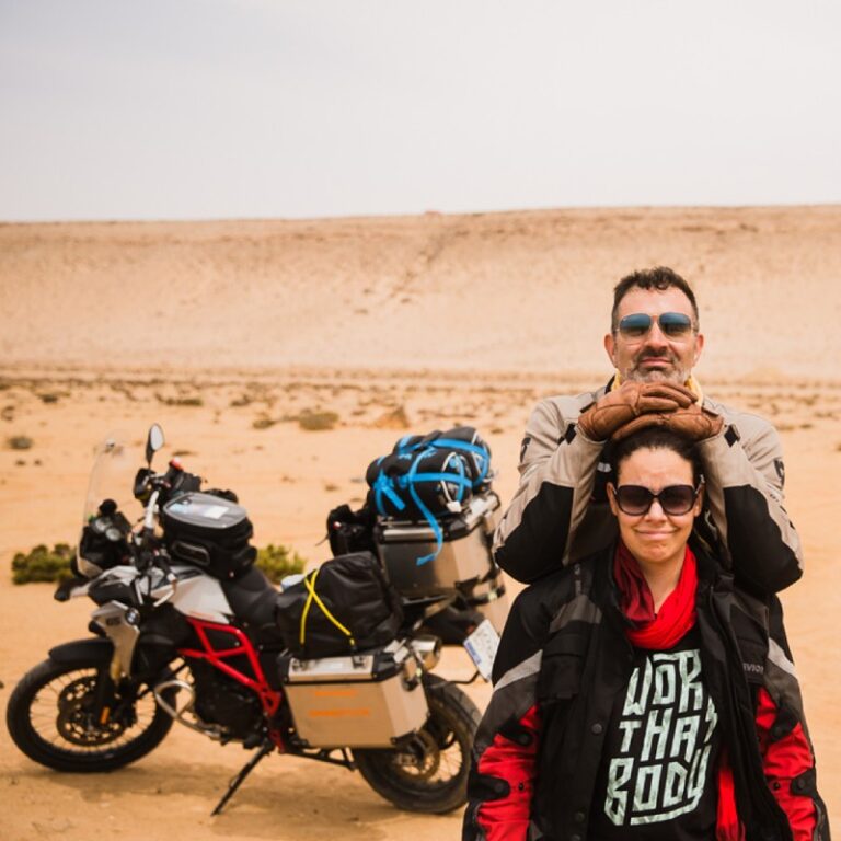 Alfonso y Ana, fotógrafos de bodas en Granada, posando junto a su moto de gran cilindrada, equipada para viajar, durante uno de sus viajes