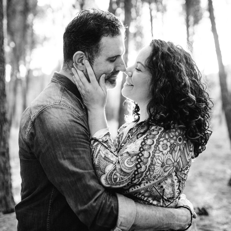 Plano medio de Alfonso y Ana en el bosque, abrazados, mirándose mutuamente en actitud alegre y cariñosa. Fotografía en blanco y negro