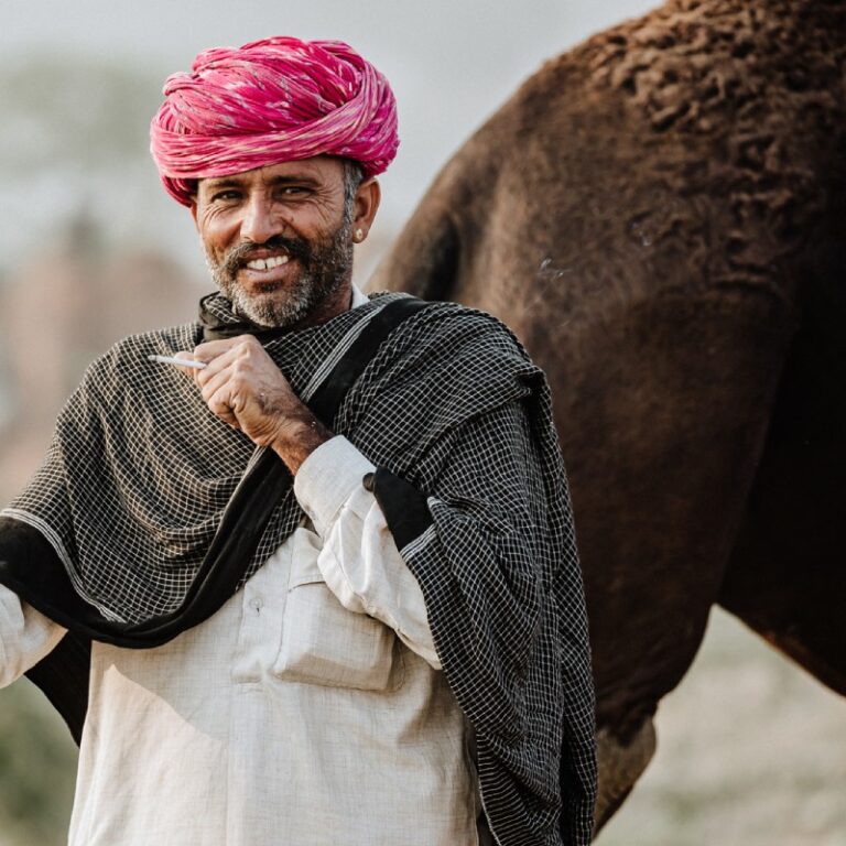 Fotografía realizada por Alfonso Azaustre, fotógrafo de bodas en Granada: hombre árabe con turbante colorido fucsia y blanco, fuamando, con su camello detrás