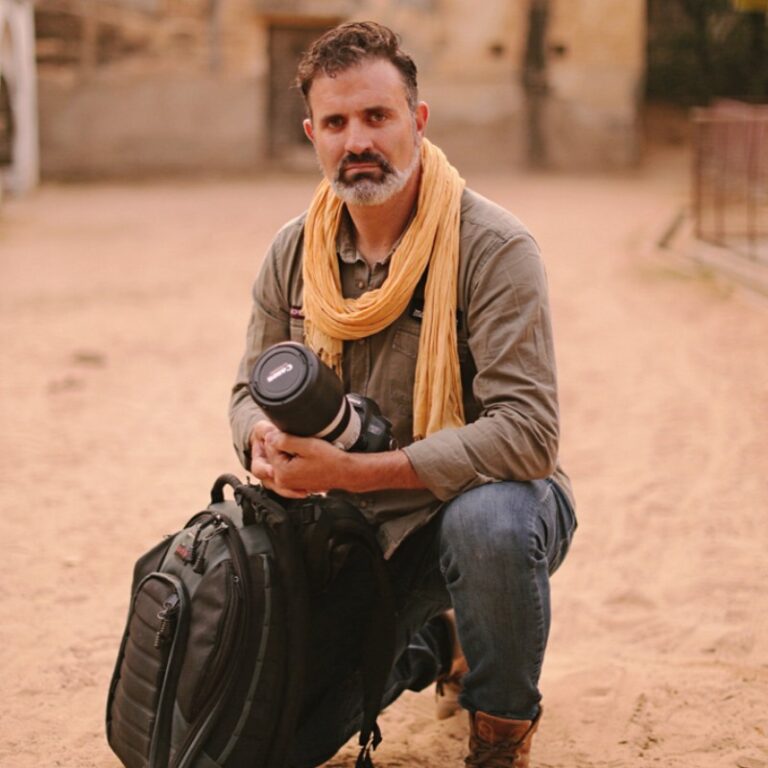 Alfonso Azaustre, fotógrafo de bodas de Granada, en cuclillas, con su mochila y su cámara de fotos, durante uno de sus viajes