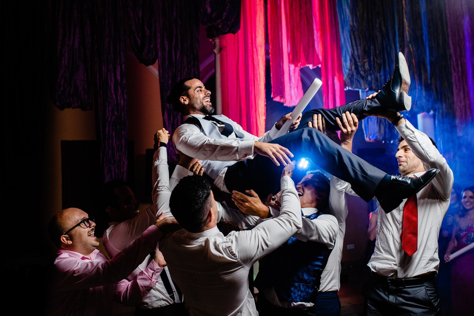 Novio siendo aupado por un grupo de amigos invitados de la boda
