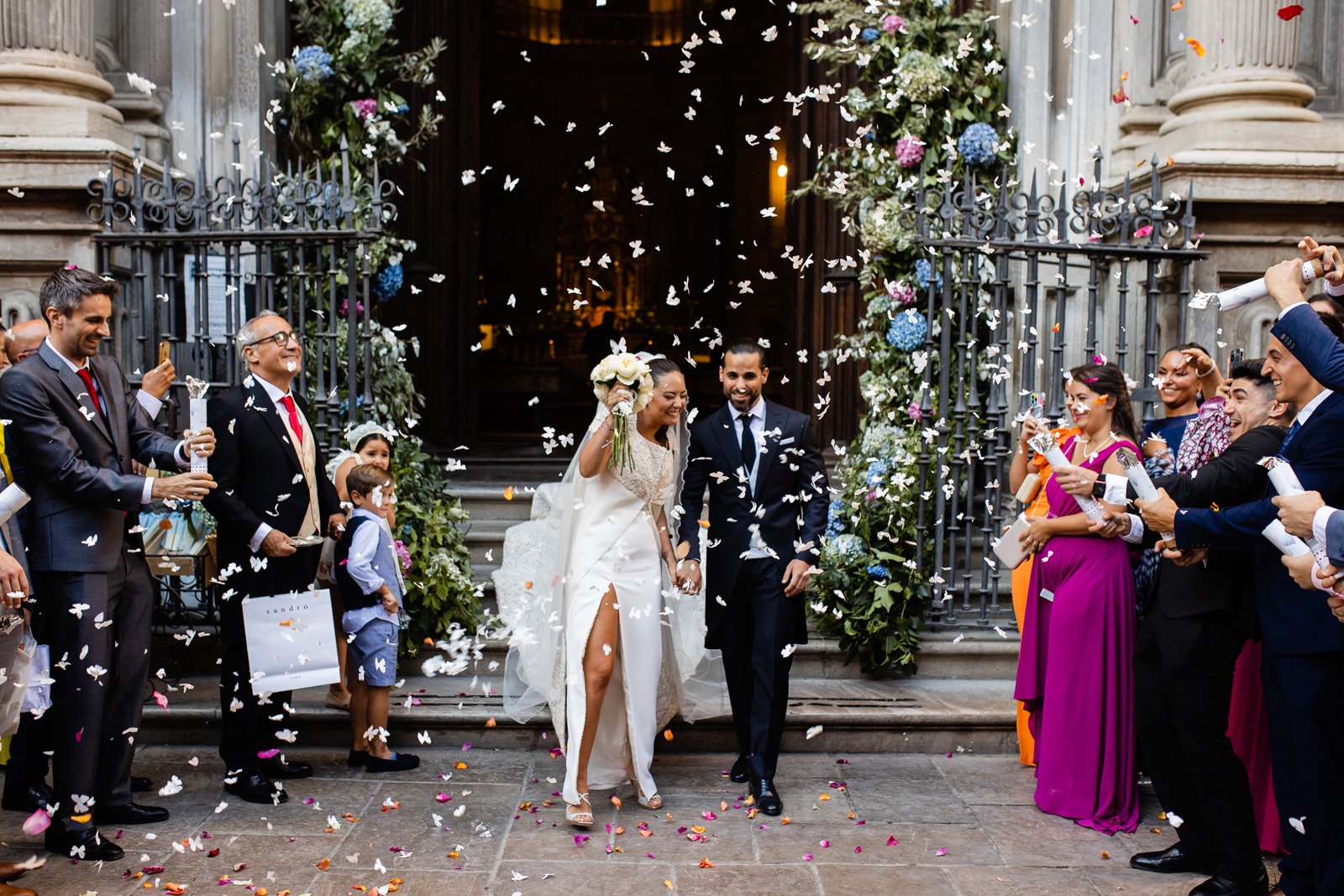 Novios saliendo de la iglesia con todos los invitados lanzándoles confeti
